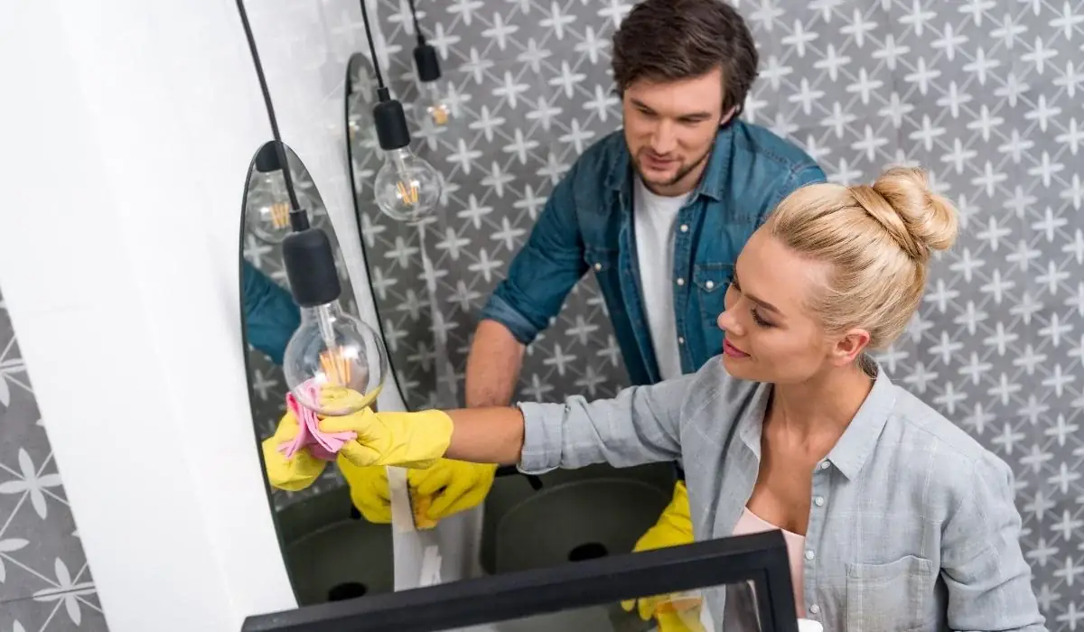 Man and woman cleaning boat cabin mirror with yellow gloves