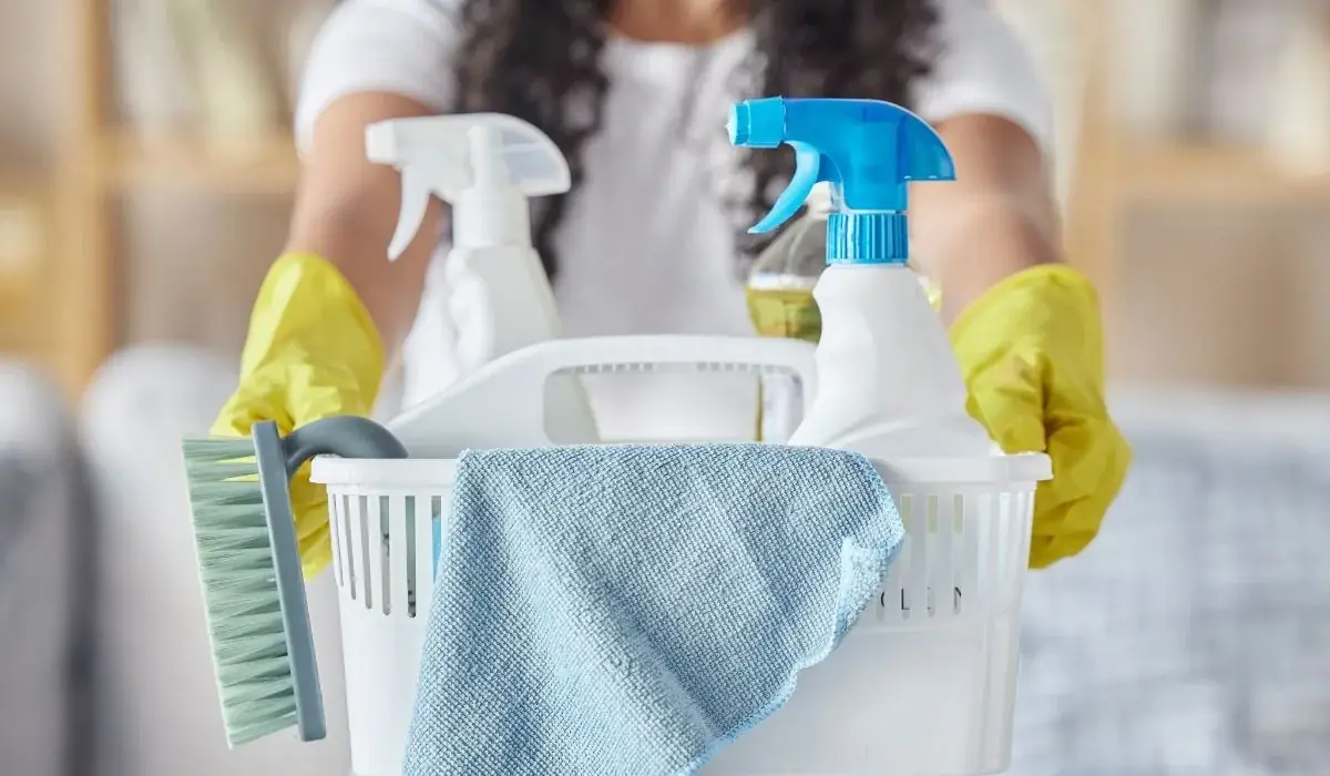 Cleaning caddy with spray bottles, microfiber cloth, scrub brush and gloved hands