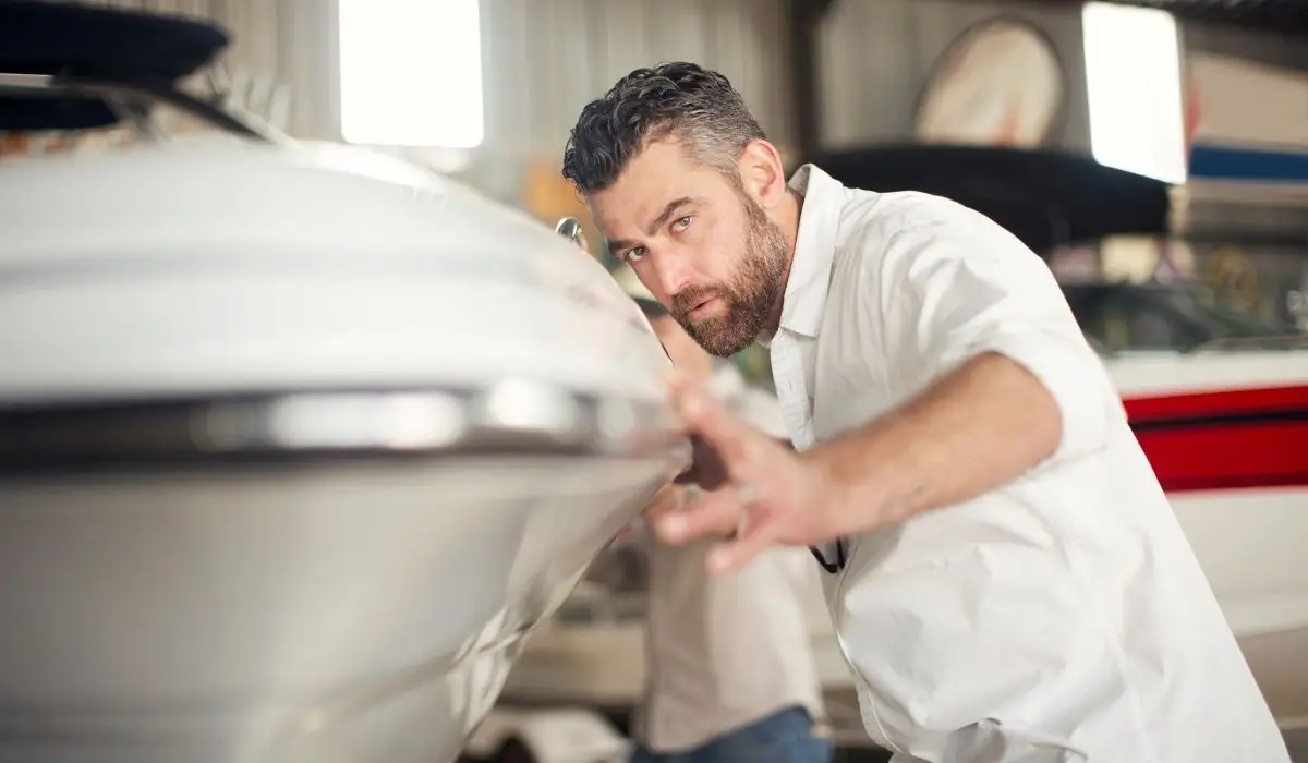 Man inspecting a boat hull during a full walkthrough for summer boat prep